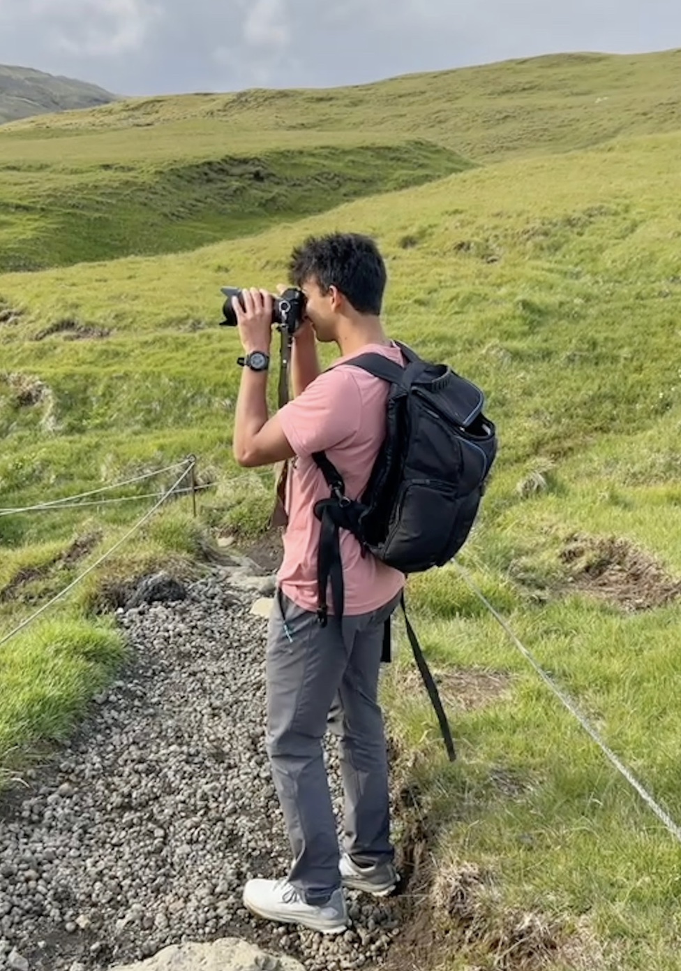 Anand taking a photograph on a grassy hillside